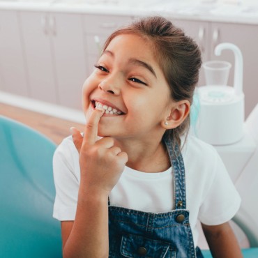 niño pequeño señalando sus dientes limpios después de una visita al dentista