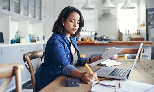 Woman working on laptop in her kitchen